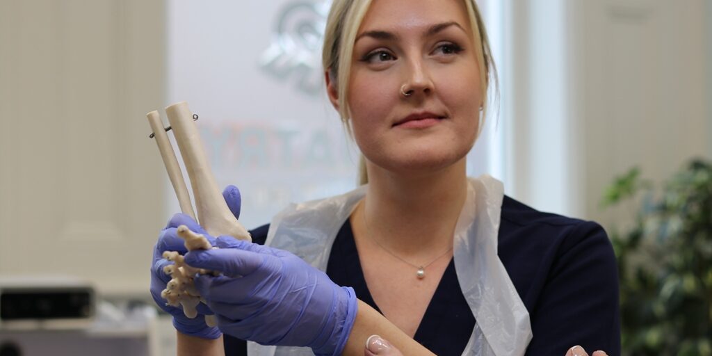 Megan at LR Podiatry, Sheffield with a model of the skeleton of a foot